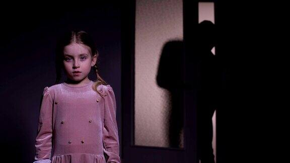 害怕的女孩独自在黑暗中可怕的小丑在后面爬行童年的恐惧