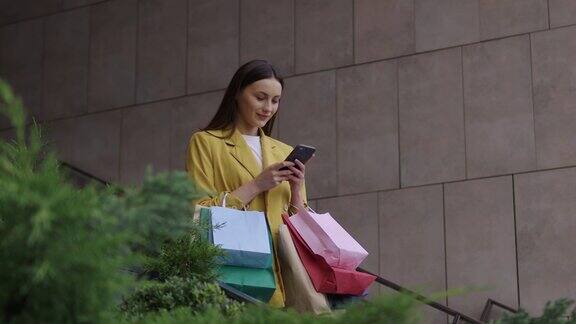 带着购物袋的女人在户外用手机发短信