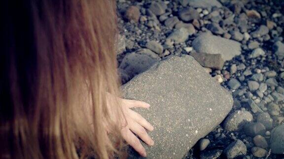 女孩在冰川泻湖触摸着海滩上的黑色岩石