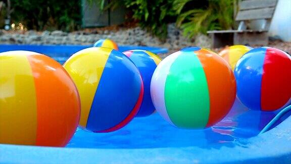 彩色的沙滩球在慢镜头中漂浮在水池中