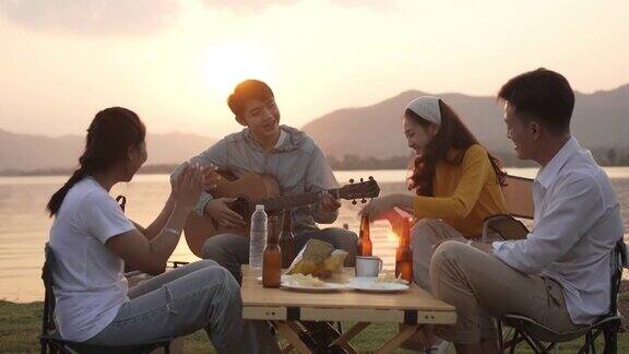 快乐的亚洲朋友团弹吉他和唱歌享受露营