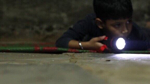 一个小男孩拿着电筒在黑暗中寻找