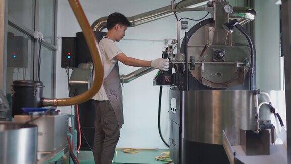 亚洲华人工匠微笑着拿着特里尔咖啡豆从咖啡烘焙机中提取咖啡豆烘焙生咖啡豆闻着检查烘焙进度
