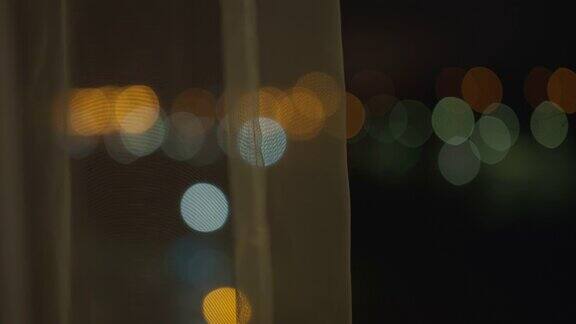 朦胧的灯光从一扇打开的窗户里在窗帘后面