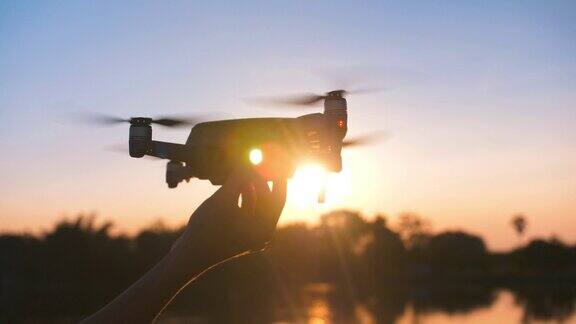 在夕阳下人手启动无人机飞向天空