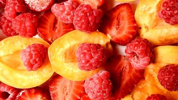 特写切片红草莓和树莓旁边的杏子在一个盘子上