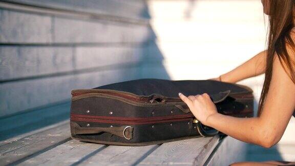 一个年轻女子在阳光下从外面的琴箱里拉出她的小提琴