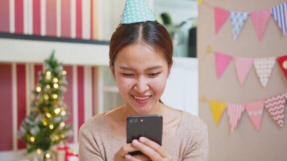 亚洲妇女在圣诞节期间用电话与朋友和家人聊天并在家里装饰新年