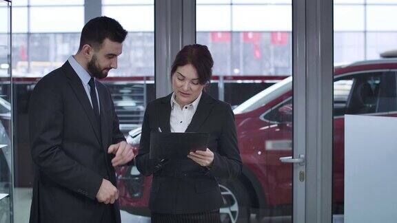男性白人销售代表给成年女商人购买汽车的合同签字二人在汽车经销处签订购销协议电影4kProRes总部