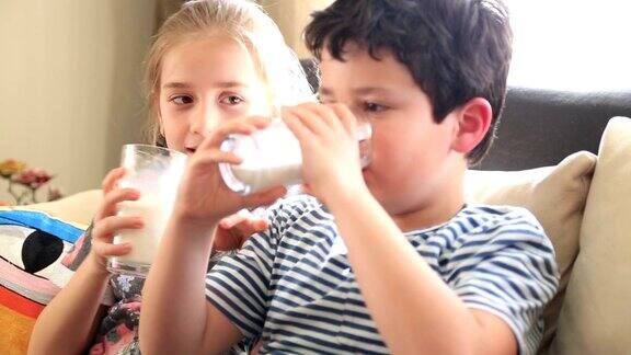 快乐的小男孩和小女孩喝着一杯牛奶