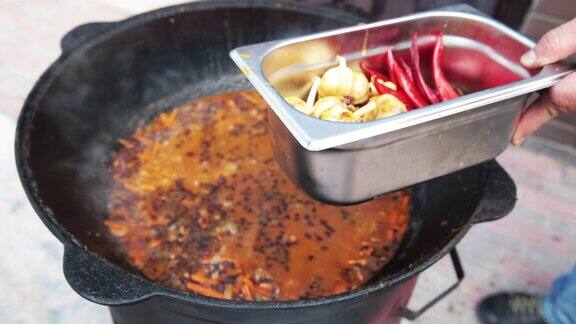 乌兹别克民族菜肴肉饭肉饭plov米饭和肉放在大锅里取出红辣椒和大蒜在大锅中烧熟过程中红辣椒和整个大蒜