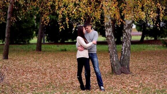一对恩爱的情侣站在一棵树旁拥抱在一起
