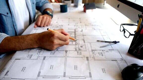 建筑师拿着铅笔工作与笔记本电脑和蓝图的建筑计划工程师素描一个建设项目
