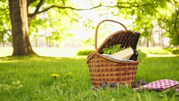 草地上铺着红色格子桌布的柳条野餐篮