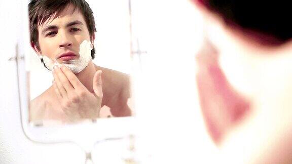 男人洗澡后对着镜子剃须