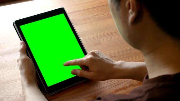 在木桌上使用绿色屏幕色键的数字平板电脑的人