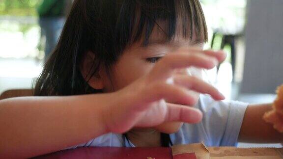 快乐的小女孩喜欢在服务店吃炸鸡和炸薯条垃圾食品和健康概念