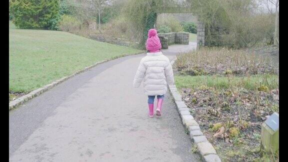 小女孩在早春的公园里散步