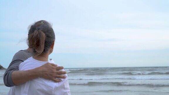 亚洲夫妇老年人退休休息拥抱在日落海滩蜜月家庭一起幸福的人的生活方式