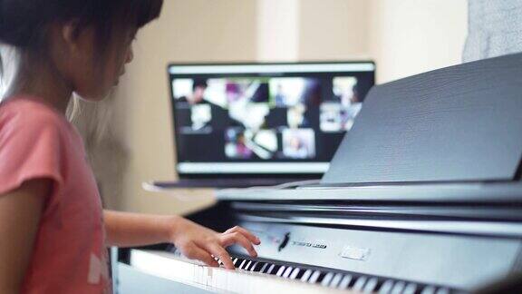 亚洲小女孩在家里学习在线钢琴课
