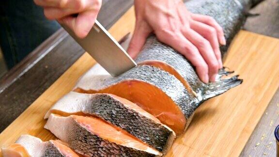 女性的手正在用刀切一条大鲑鱼