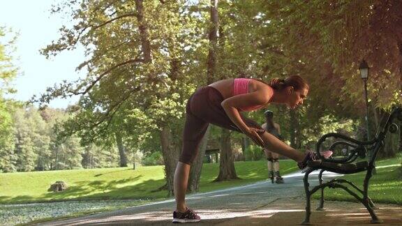 一位女跑步者在公园的长椅上伸展她的双腿