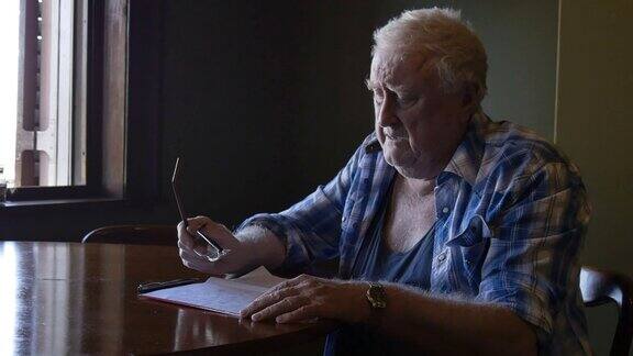 悲伤的退休老人在餐桌上思考信