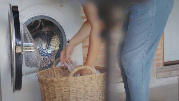 做家务的亚洲妇女洗完衣服后妇女用手从洗衣机滚筒中取出衣服在家里烘干