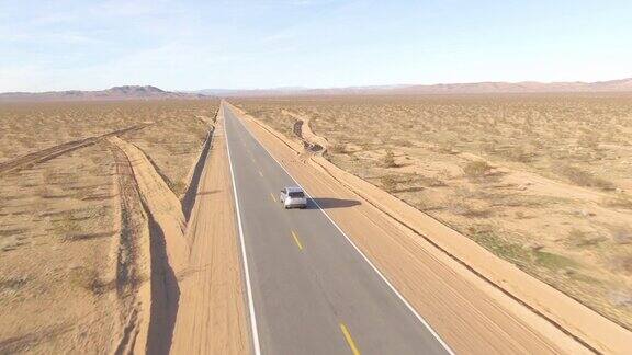 航拍:在一辆银色SUV后面飞过崎岖的莫哈韦沙漠
