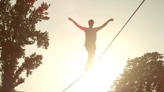 慢镜头:夏日日落时分一名男子走在高绳上