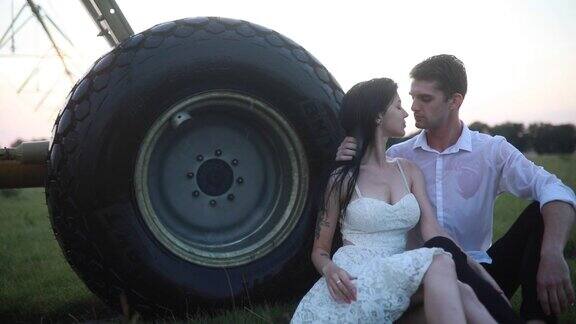 相爱的情侣在农用喷雾器附近的水滴下拥抱