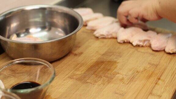 厨师用去皮刀在鸡翅上划痕准备腌制