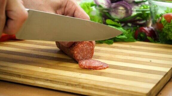 厨师在木板上用刀切意大利腊肠