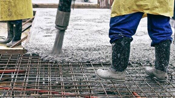 建筑工人移动软管将混凝土注入钢筋网的开口