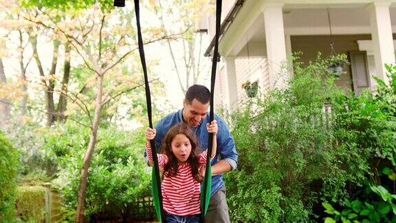 父亲推着女儿在花园里荡秋千