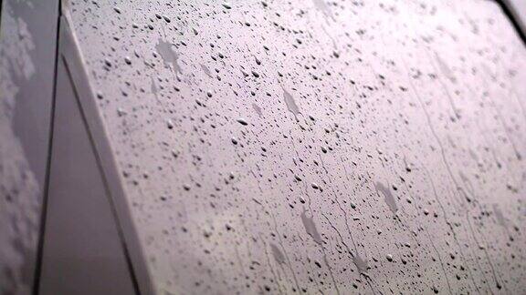 特写镜头雨点在汽车的玻璃窗上滴落下来雨下得很大下着倾盆大雨雨滴落在汽车玻璃上
