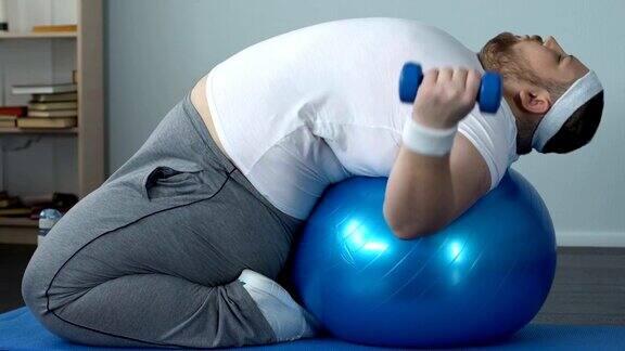 有动力的胖子躺在健身球上举哑铃减肥计划