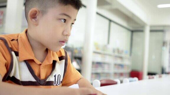 一个亚洲小男孩在白纸上写字