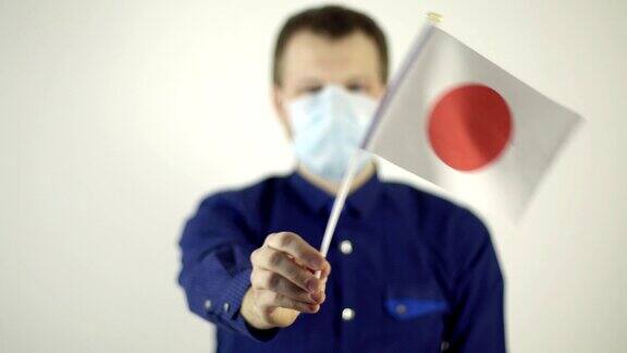 一名戴着防毒面具的男子挥舞着日本国旗国家冠状病毒病概念2019冠状病毒病大流行
