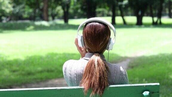 亚洲女人在公园里听音乐放松
