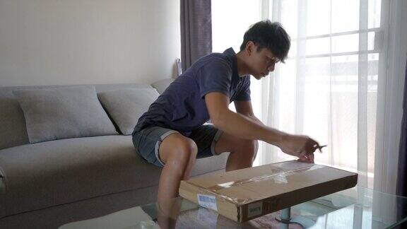 一个亚洲男人打开一个盒子里面装着未完成的桌子