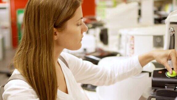 年轻女子在商店购买厨房电器拿起油炸格栅白色家电背景