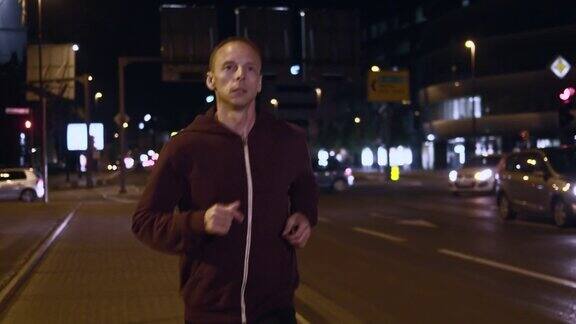 SLOMOTS男子晚上在城市街道上慢跑