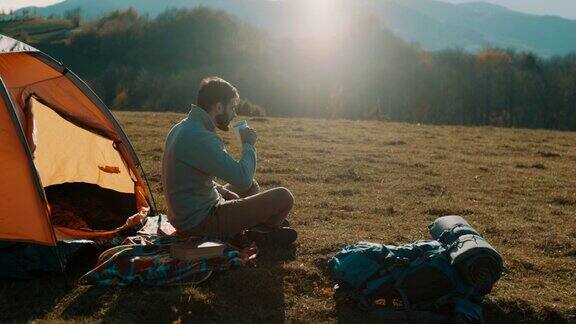 一个人坐在山上喝着咖啡野营