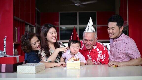 中国多代家庭在家里为爷爷孙子吹生日蜡烛庆祝生日