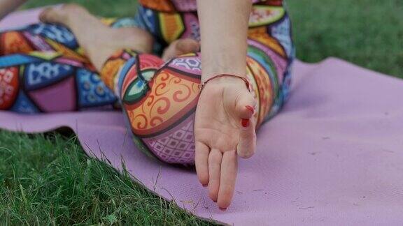 年轻女子在公园里摆莲花姿势冥想手的特写镜头