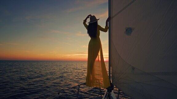身着黄色长裙的女子在夕阳下欣赏着风帆