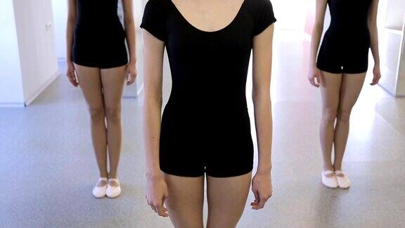 三个女孩穿着同样的黑色服装站在舞蹈教室里