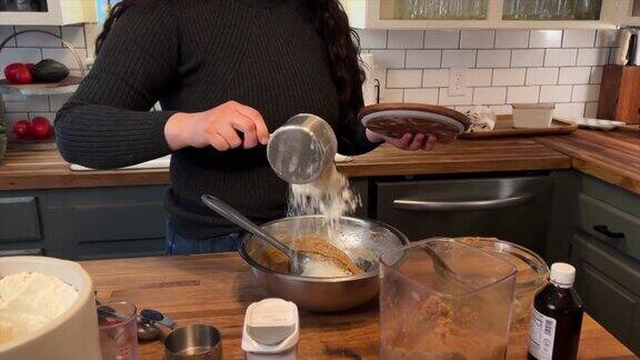 年轻女子家庭面包师添加成分混合碗制作新鲜饼干