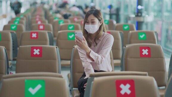 年轻的亚洲女性在机场使用手机时戴上口罩